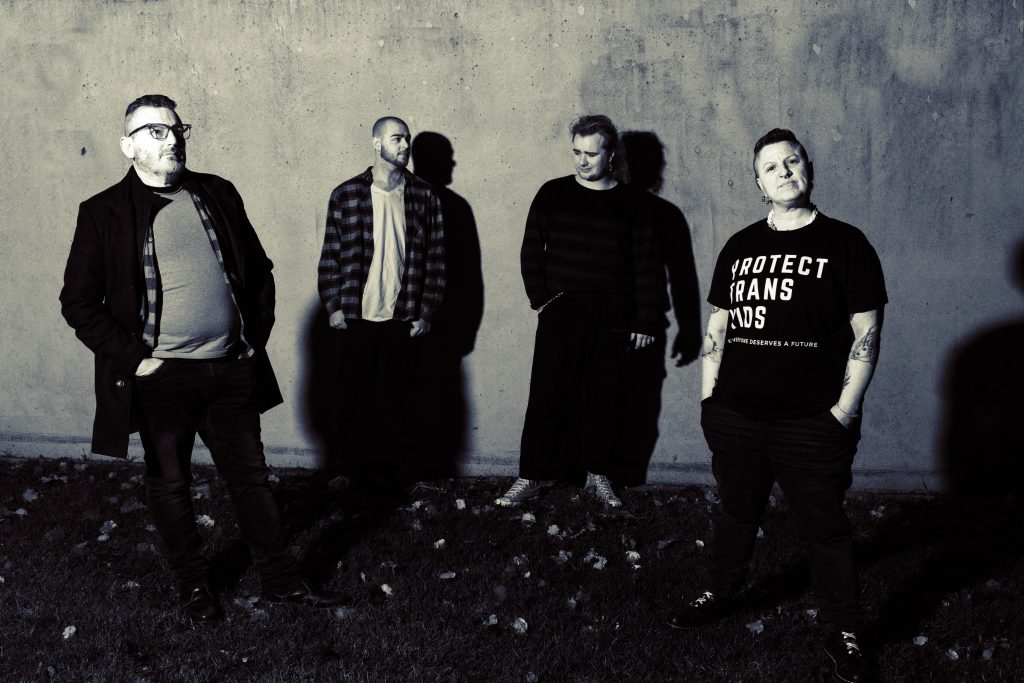 nonbinarycode band picture The Hardman, Racso, Sorrento, and InkBits are all standing looking in different directions.